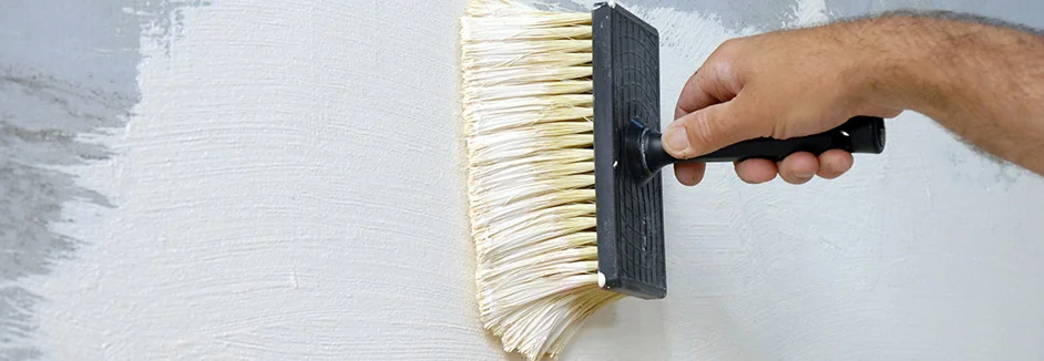 Person streicht Wand mit Quast